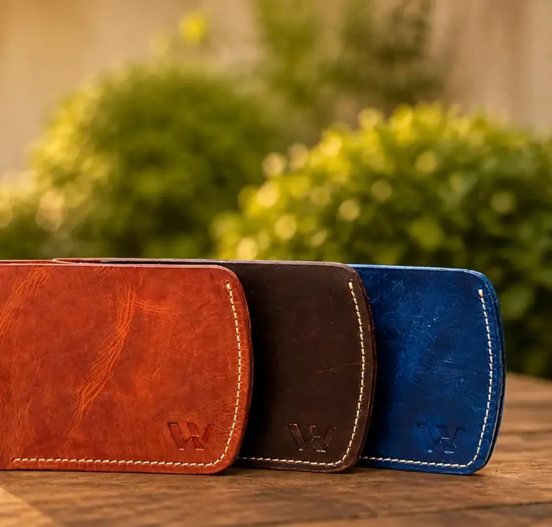 Three Wrenza handcrafted full-grain leather wallets in brown, dark brown, and blue colors